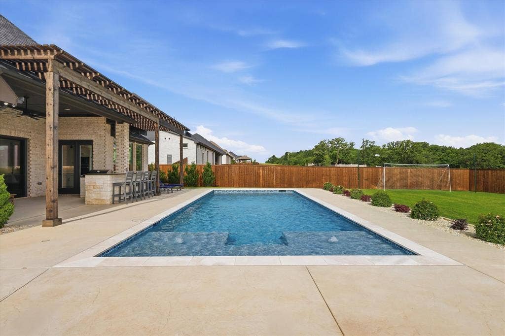 Rectangular in-ground swimming pool with integrated steps, surrounded by a light-toned concrete patio