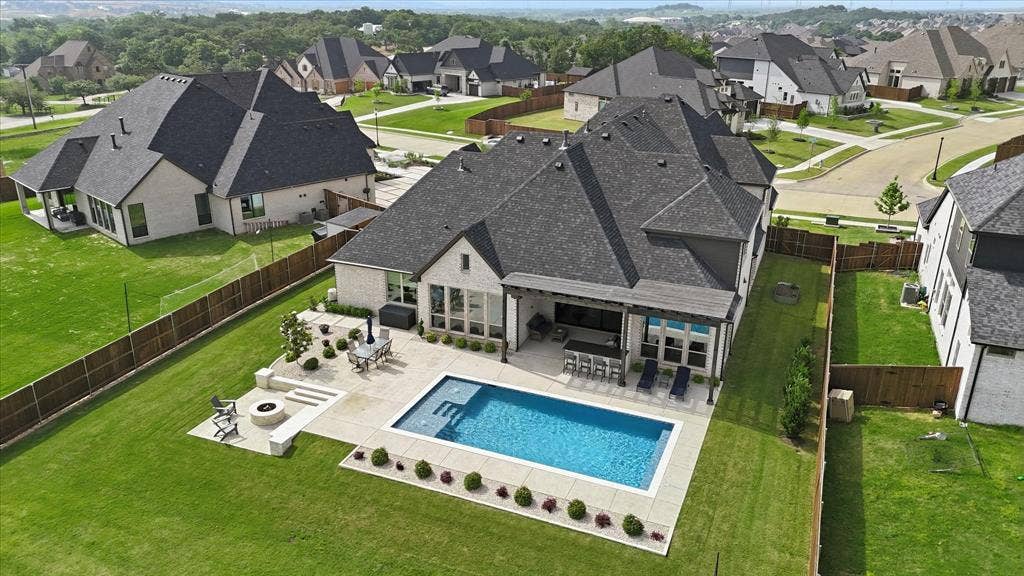 Rear exterior featuring a swimming pool with integrated spa, an outdoor kitchen with bar seating, a fire pit area, and a covered patio