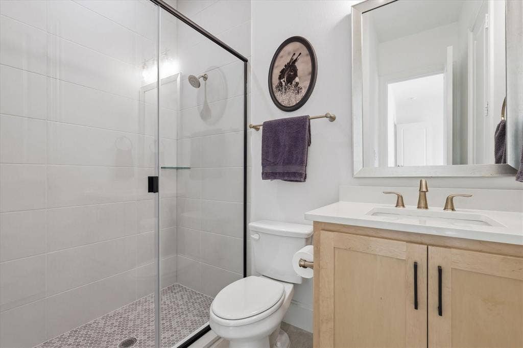 Modern bathroom featuring a walk-in shower with clear glass enclosure and black trim, white subway tile walls, and a mosaic tile shower floor