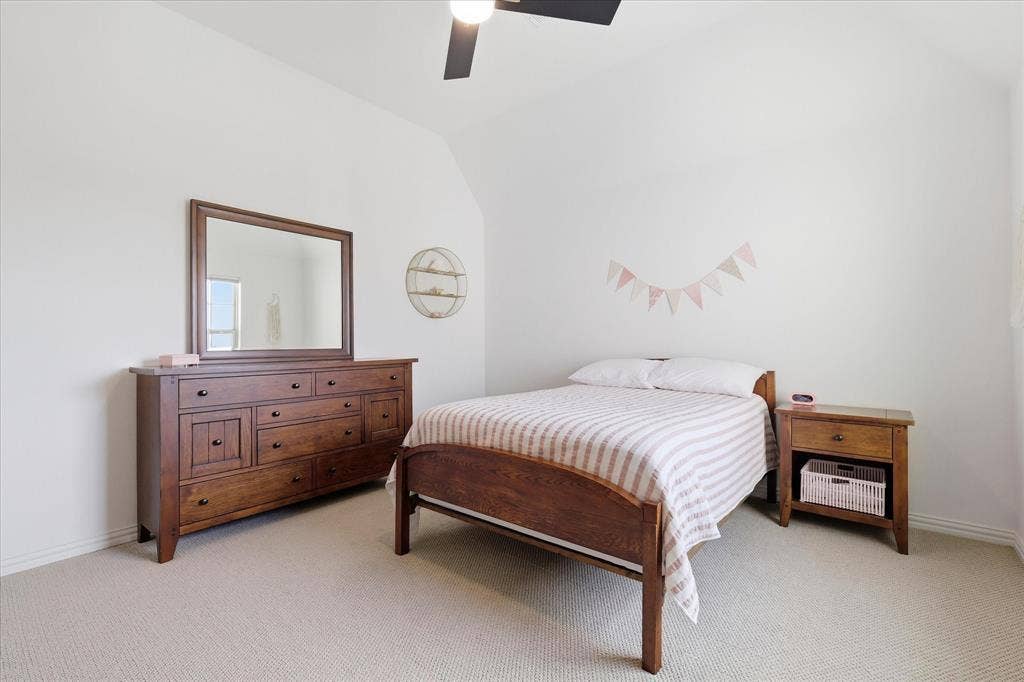 Bedroom featuring light neutral carpeting, white painted walls, a vaulted ceiling, and a ceiling fan
