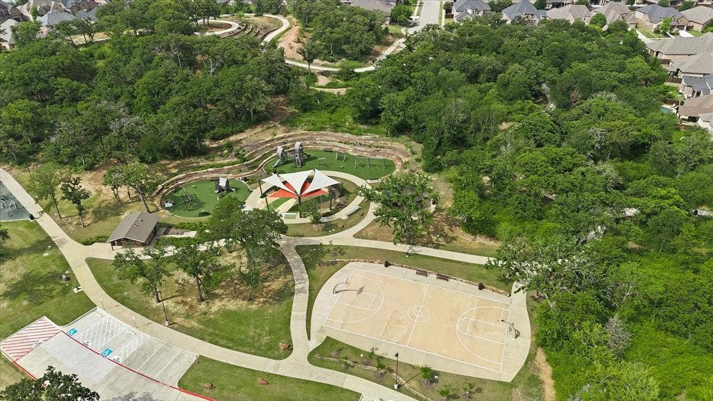 Community park area featuring a full basketball court, a covered playground structure, and walking paths
