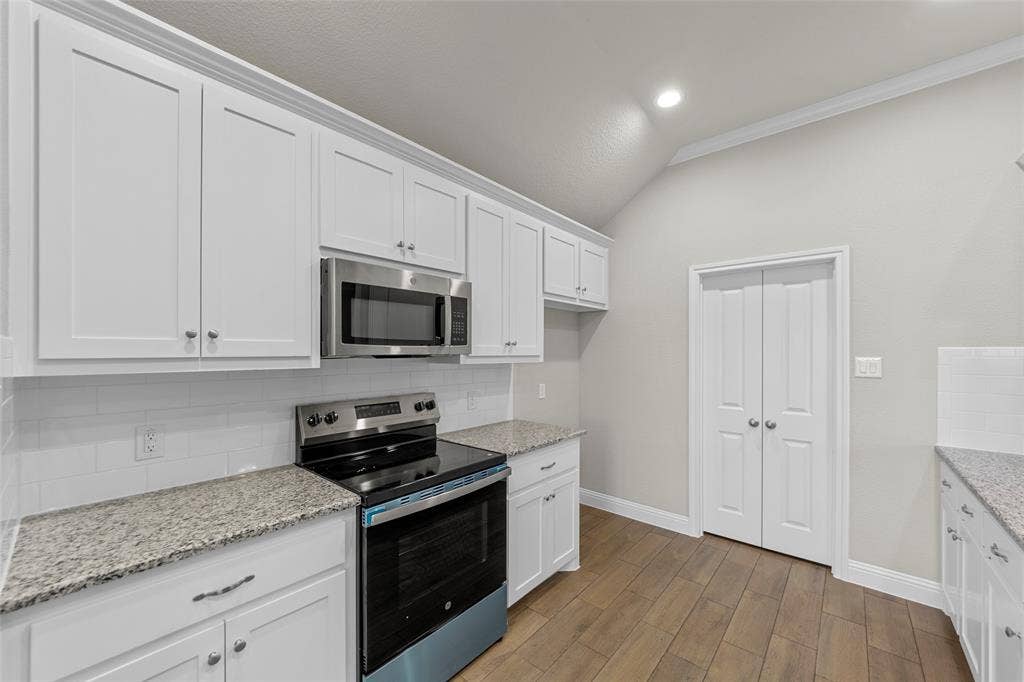 18310 CHIPPEWA Court, Terrell, TX 75160 Kitchen featuring white shaker cabinetry, stainless steel appliances, speckled stone countertops, and a subway tile backsplash