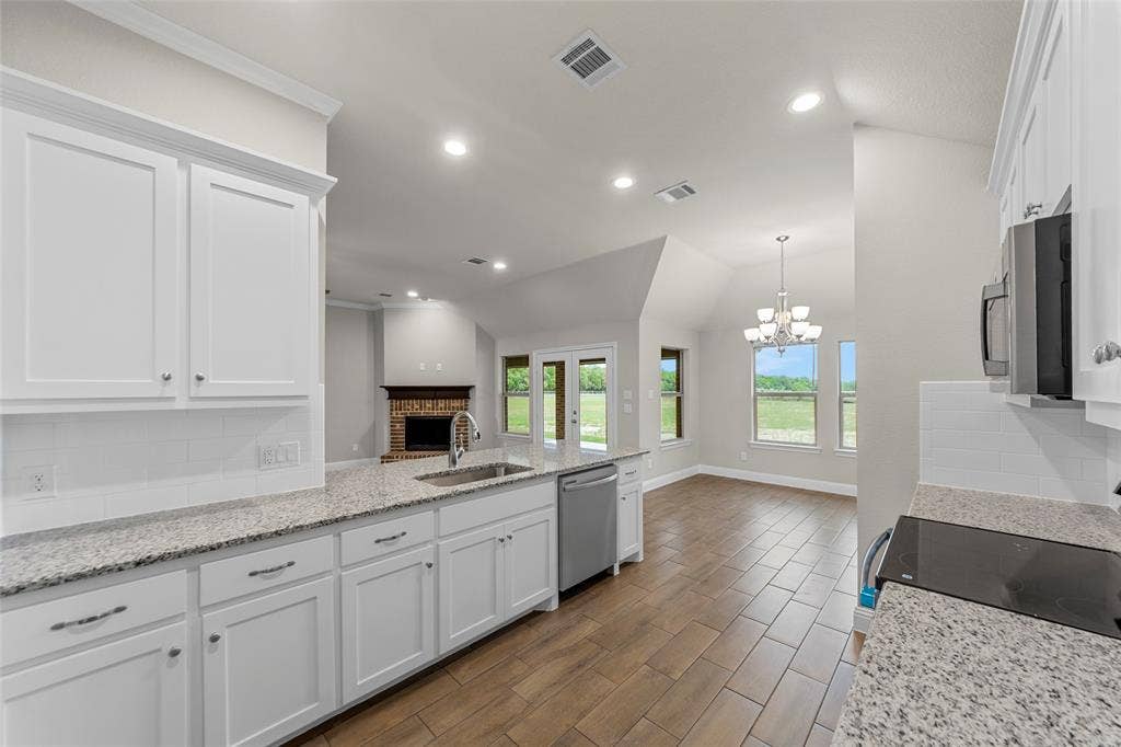 18310 CHIPPEWA Court, Terrell, TX 75160 Kitchen featuring white cabinetry, light-toned granite countertops, a stainless steel sink with a gooseneck faucet, and wood-finish flooring