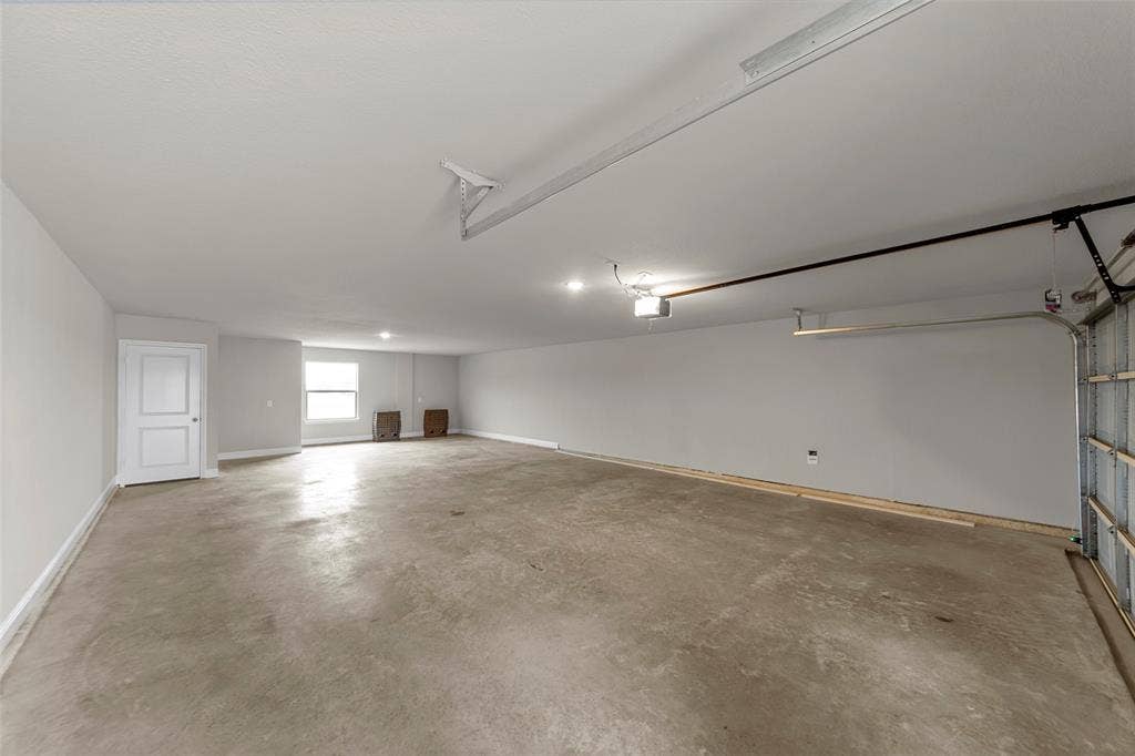 18310 CHIPPEWA Court, Terrell, TX 75160 Spacious garage featuring a concrete floor, bright overhead lighting, and a white interior door