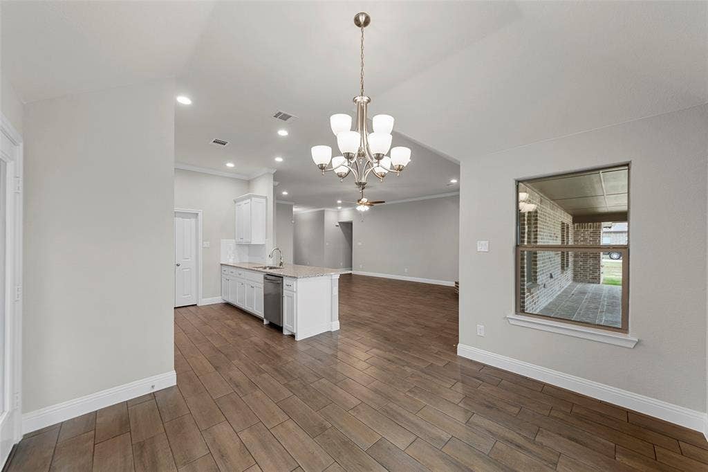 18310 CHIPPEWA Court, Terrell, TX 75160 Open-concept living area featuring wood-finish flooring, a kitchen island with integrated sink, recessed lighting, and a decorative chandelier