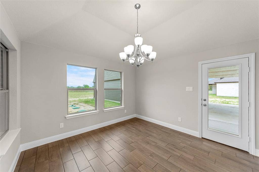 18310 CHIPPEWA Court, Terrell, TX 75160 Open-concept room featuring wood-finish tile flooring, multiple windows, and a glass-paneled exterior door