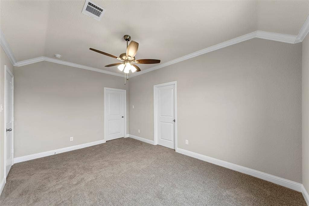 18310 CHIPPEWA Court, Terrell, TX 75160 Carpeted room featuring a vaulted ceiling with crown molding, two panel doors, a ceiling fan with light kit, and neutral wall paint