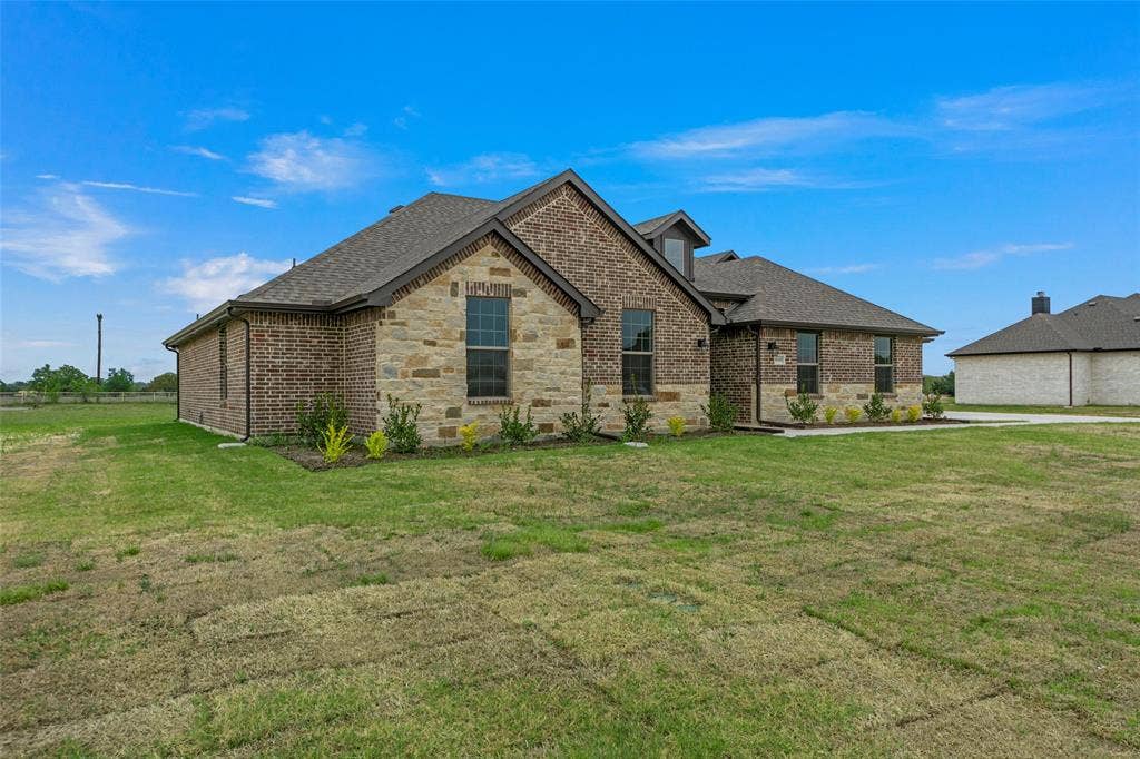 18310 CHIPPEWA Court, Terrell, TX 75160 Traditional-style residence featuring brick and stone exterior, dark roof shingles, an integrated dormer, and multiple windows