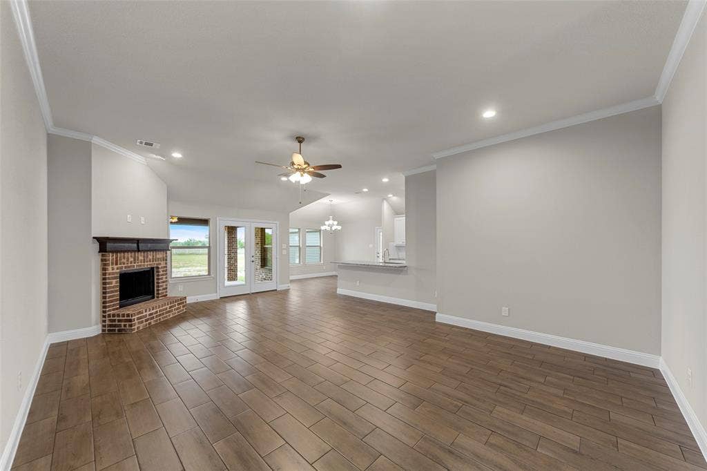 18310 CHIPPEWA Court, Terrell, TX 75160 Expansive living area featuring wood-finish tile flooring and a brick fireplace with a dark wood mantel