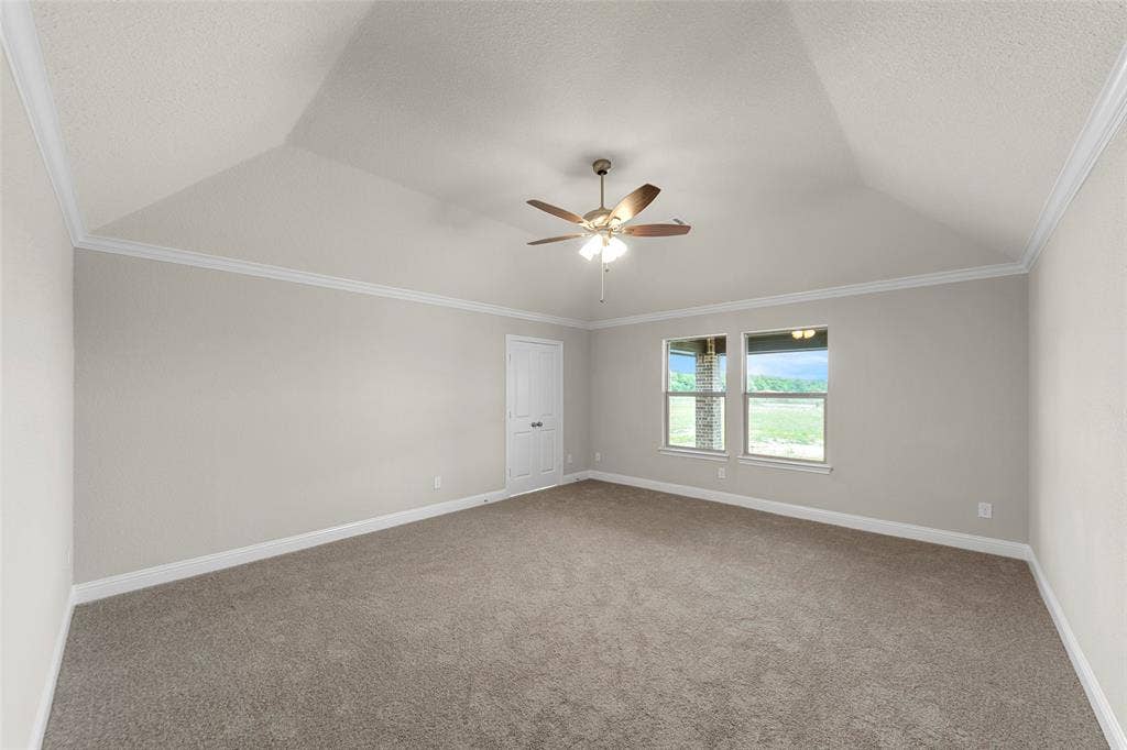 18310 CHIPPEWA Court, Terrell, TX 75160 Vaulted ceiling featuring a ceiling fan, crown molding, double windows, a paneled door, and carpet flooring