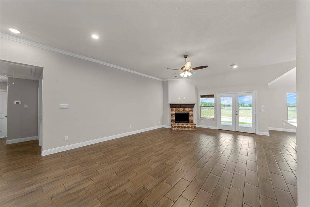 18310 CHIPPEWA Court, Terrell, TX 75160 Spacious living area featuring wood-finish tile flooring, a brick fireplace with a wood mantle, and French doors