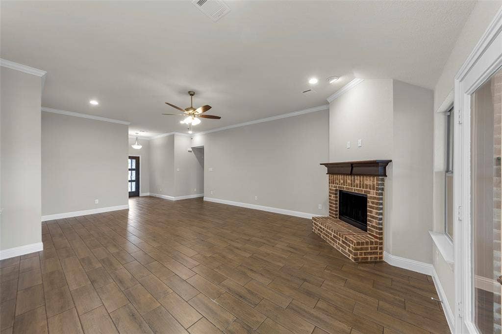18310 CHIPPEWA Court, Terrell, TX 75160 Expansive open-concept living area featuring wood-finish flooring, a brick fireplace with a dark wood mantel, recessed lighting, and crown molding