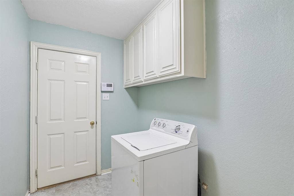 4124 Cory Lee Court, Arlington, TX 76015 Laundry area featuring overhead cabinetry, light blue wall paint, and a six-panel interior door