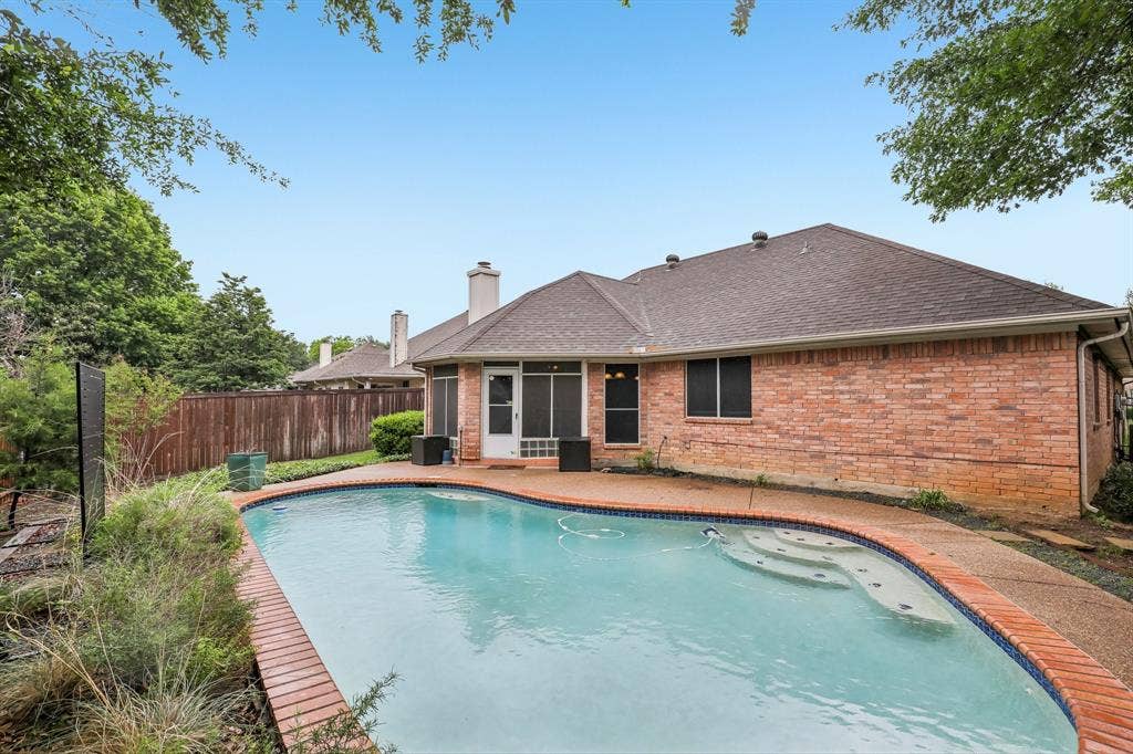 4124 Cory Lee Court, Arlington, TX 76015 Curved swimming pool featuring an integrated spa, brick coping, and a textured concrete deck