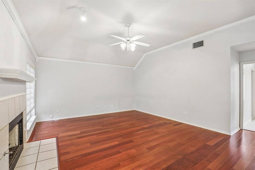 4124 Cory Lee Court, Arlington, TX 76015 Living area featuring rich wood-finish flooring, a white tile-surround fireplace with a mantel, a vaulted ceiling, and a ceiling fan