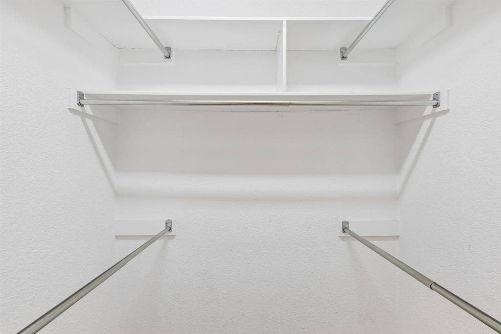 4124 Cory Lee Court, Arlington, TX 76015 White-painted closet interior featuring built-in shelving, multiple hanging rods, and textured walls