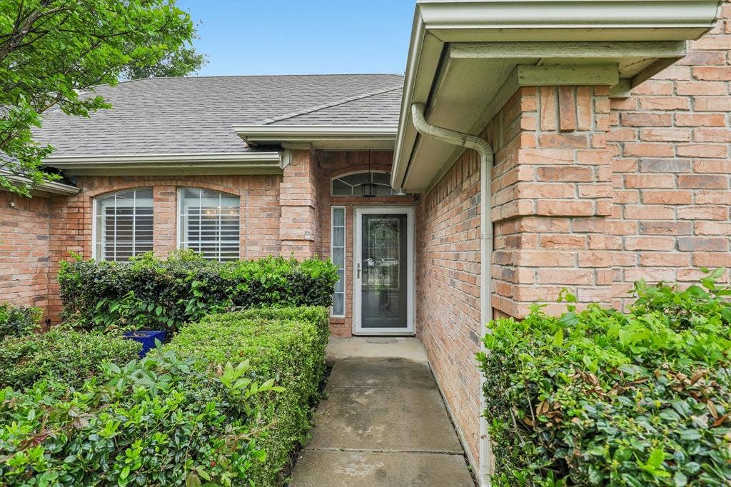 4124 Cory Lee Court, Arlington, TX 76015 Brick facade home featuring a gabled roof, white gutters, and a covered entry