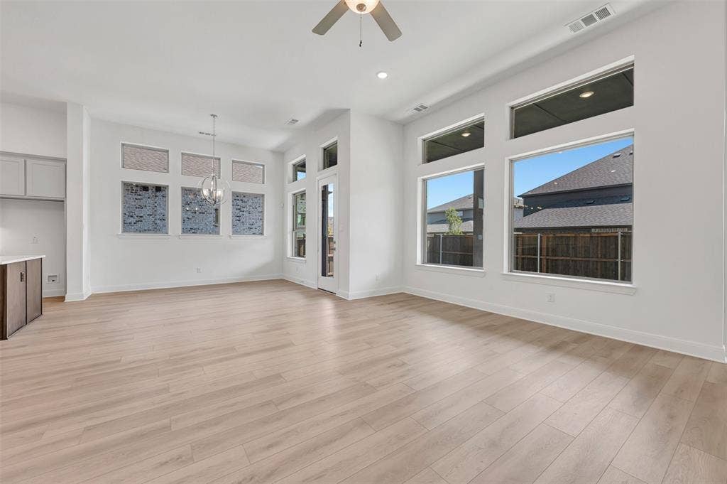 1611 Cedarberry Drive, Northlake, TX 76226 Expansive open-concept room featuring light wood-finish flooring, numerous large windows, a built-in ceiling fan, recessed lighting, and a contemporary chandelier