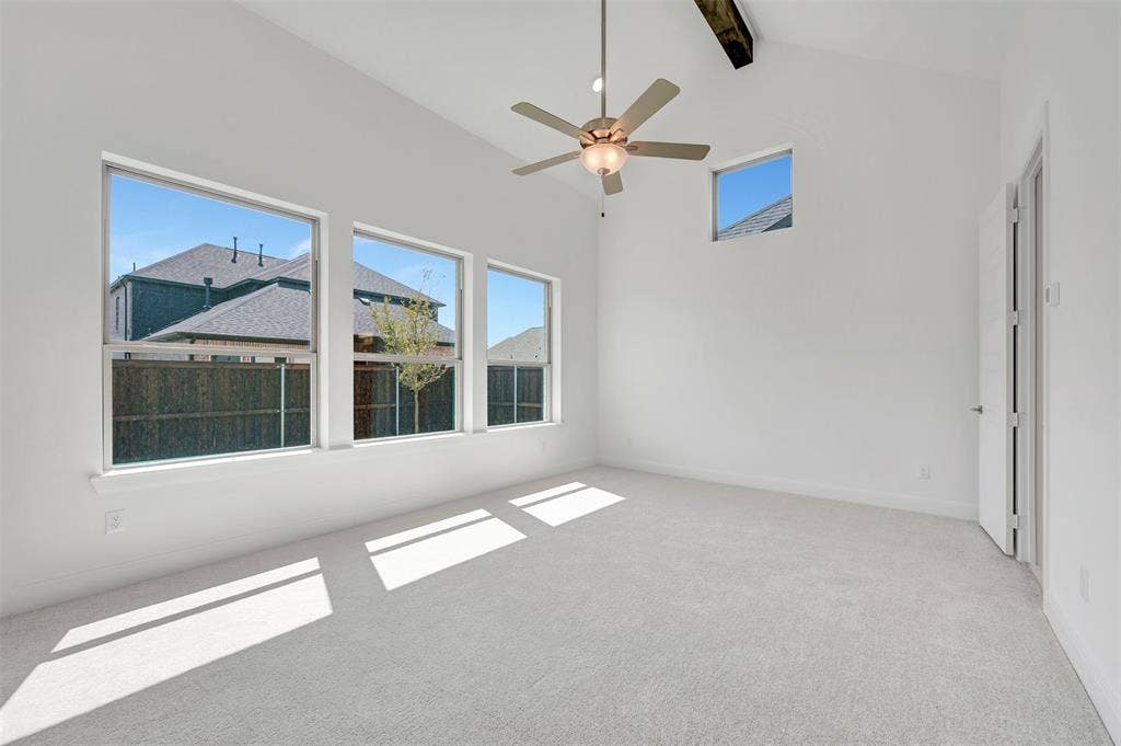 1611 Cedarberry Drive, Northlake, TX 76226 Vaulted ceiling with an exposed wood beam accent, light gray carpet flooring, multiple large windows, and a ceiling fan with integrated lighting