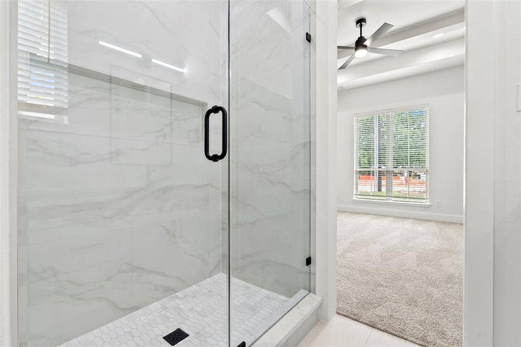 Glass-enclosed shower featuring white marble-look tile walls and a hexagonal tile floor