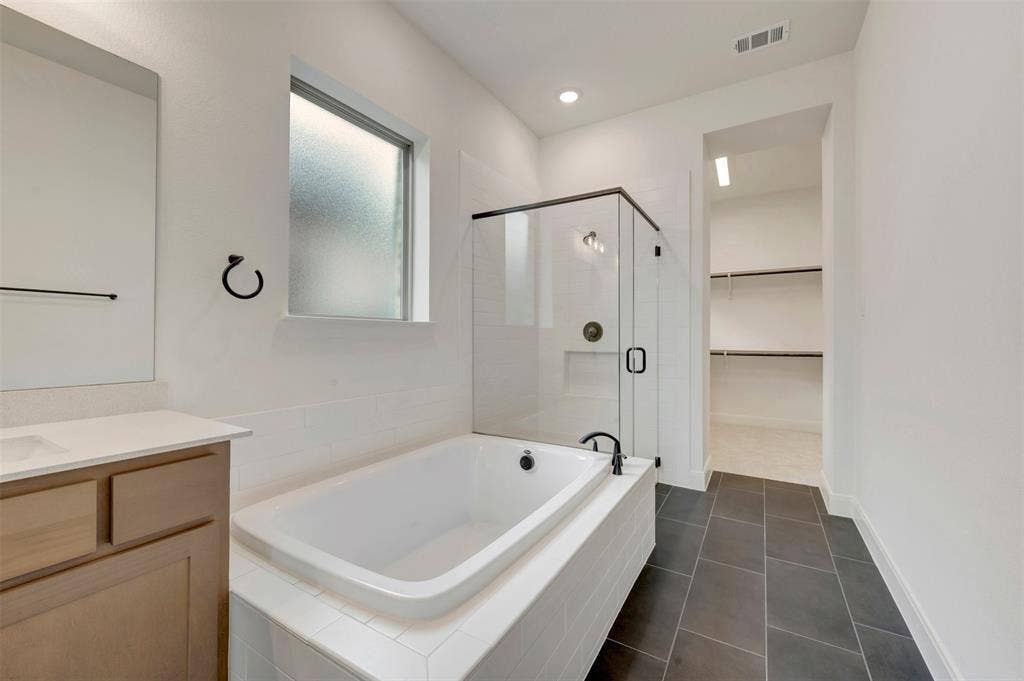 1605 Cedarberry Drive, Northlake, TX 76226 Built-in soaking tub, glass-enclosed shower, single vanity with light-tone cabinetry, dark tile flooring, and recessed lighting