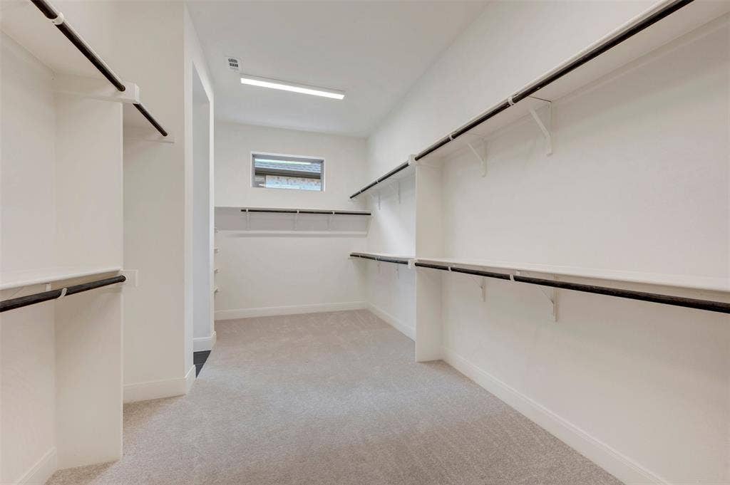 1605 Cedarberry Drive, Northlake, TX 76226 Expansive walk-in closet featuring light-colored carpeting, multiple hanging rods, extensive shelving, and a transom window for natural light