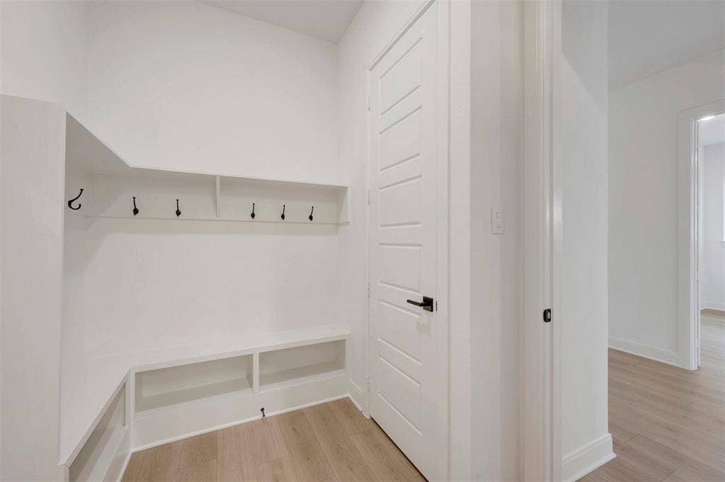 1605 Cedarberry Drive, Northlake, TX 76226 Built-in shelving with hooks, integrated bench seating, wood-finish flooring, white paneled door with matte black hardware, and crisp white walls