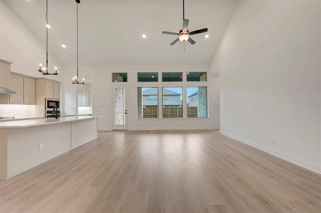 1605 Cedarberry Drive, Northlake, TX 76226 Open-concept living space with soaring vaulted ceilings, abundant natural light from transom windows, and wide-plank wood-finish flooring throughout