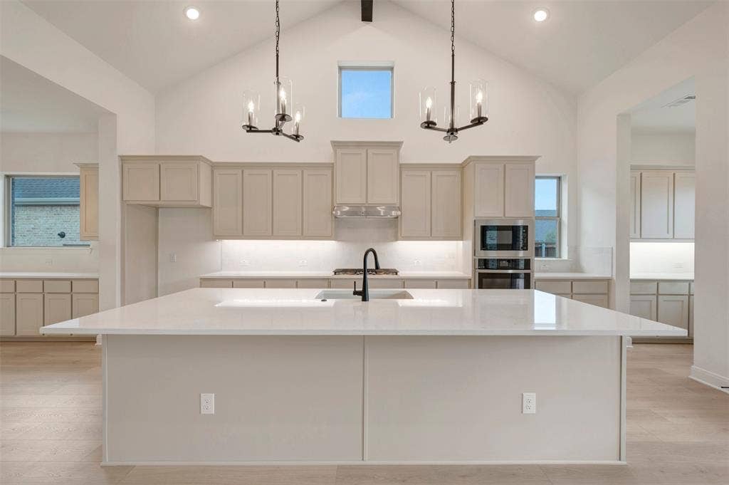 1605 Cedarberry Drive, Northlake, TX 76226 Vaulted ceiling with exposed beam, dual chandeliers, large center island with integrated sink, built-in oven and microwave, and extensive cabinetry with under-cabinet lighting