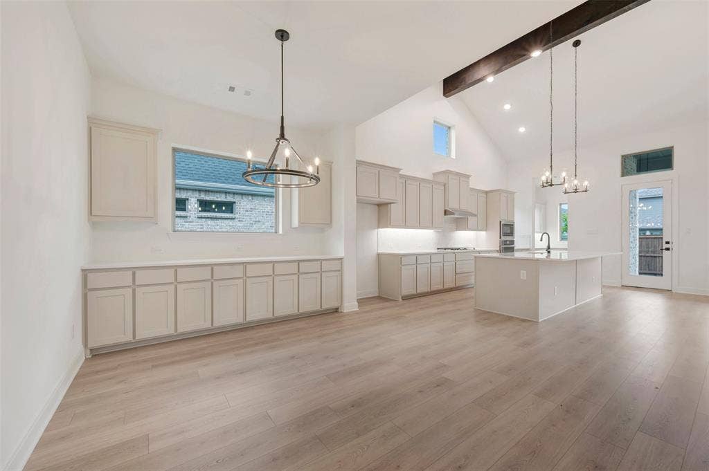 1605 Cedarberry Drive, Northlake, TX 76226 Vaulted ceilings with exposed beam, wood-finish flooring, kitchen island with sink, white shaker cabinetry, and stainless steel appliances