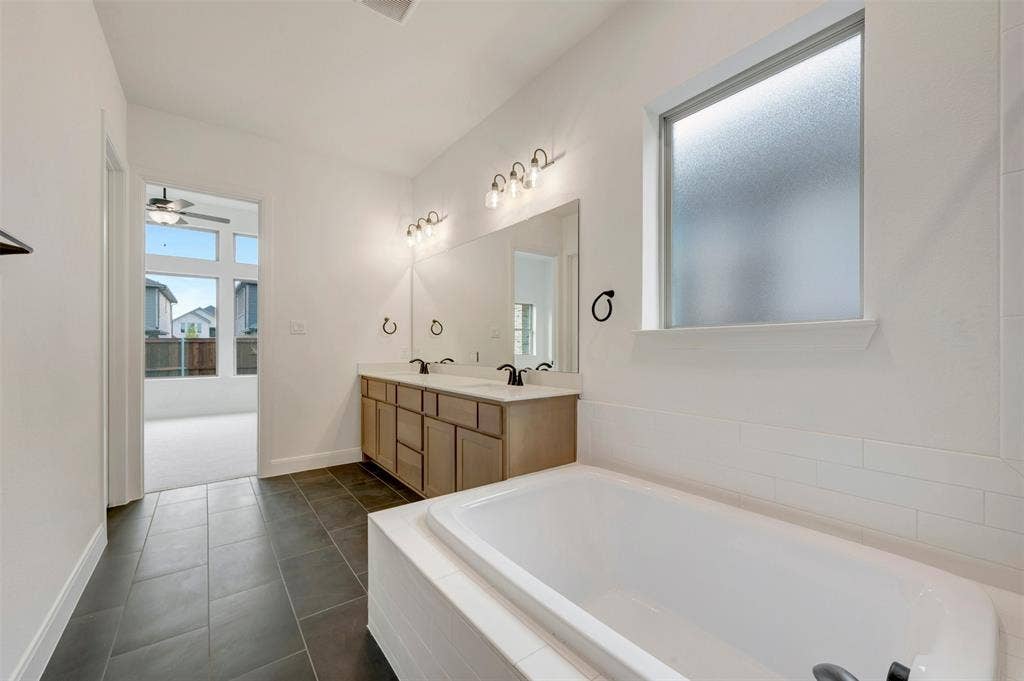 1605 Cedarberry Drive, Northlake, TX 76226 Dual vanity with wood-finish cabinetry, built-in soaking tub, large format tile flooring, and a privacy window