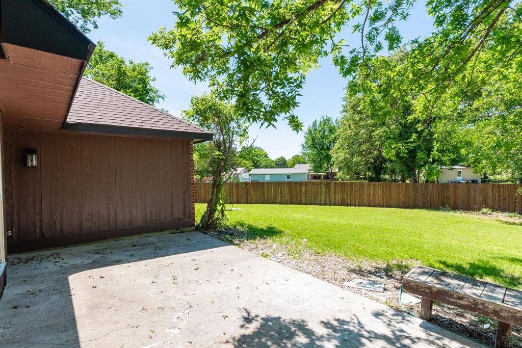 Expansive backyard featuring a manicured lawn, a full privacy fence, and a concrete patio