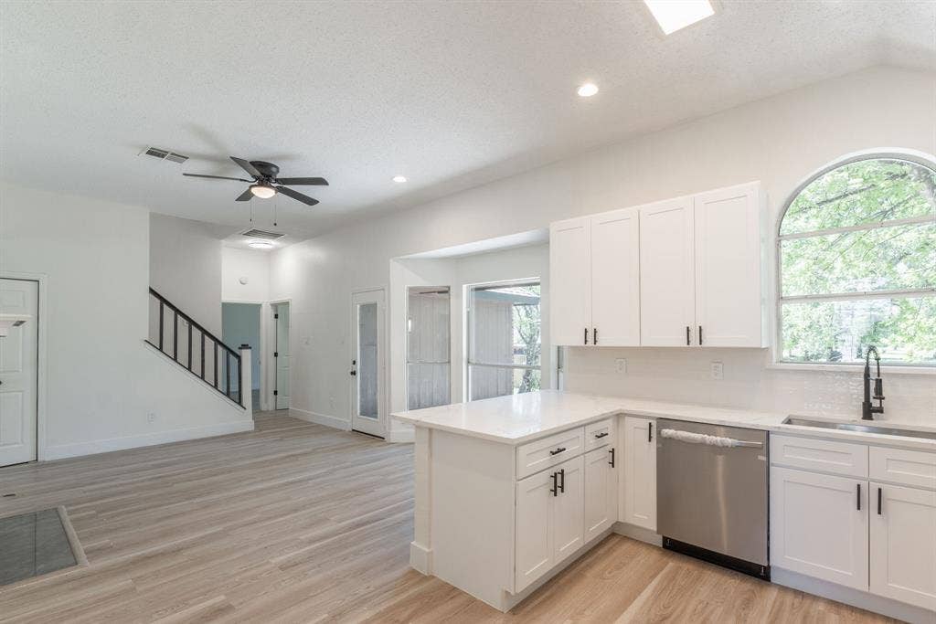 Modern kitchen featuring white shaker cabinetry, stainless steel appliances, and light-tone wood-finish flooring