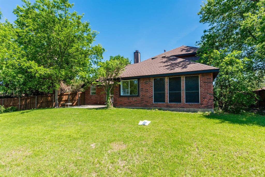 Spacious rear lawn with mature trees and a privacy fence
