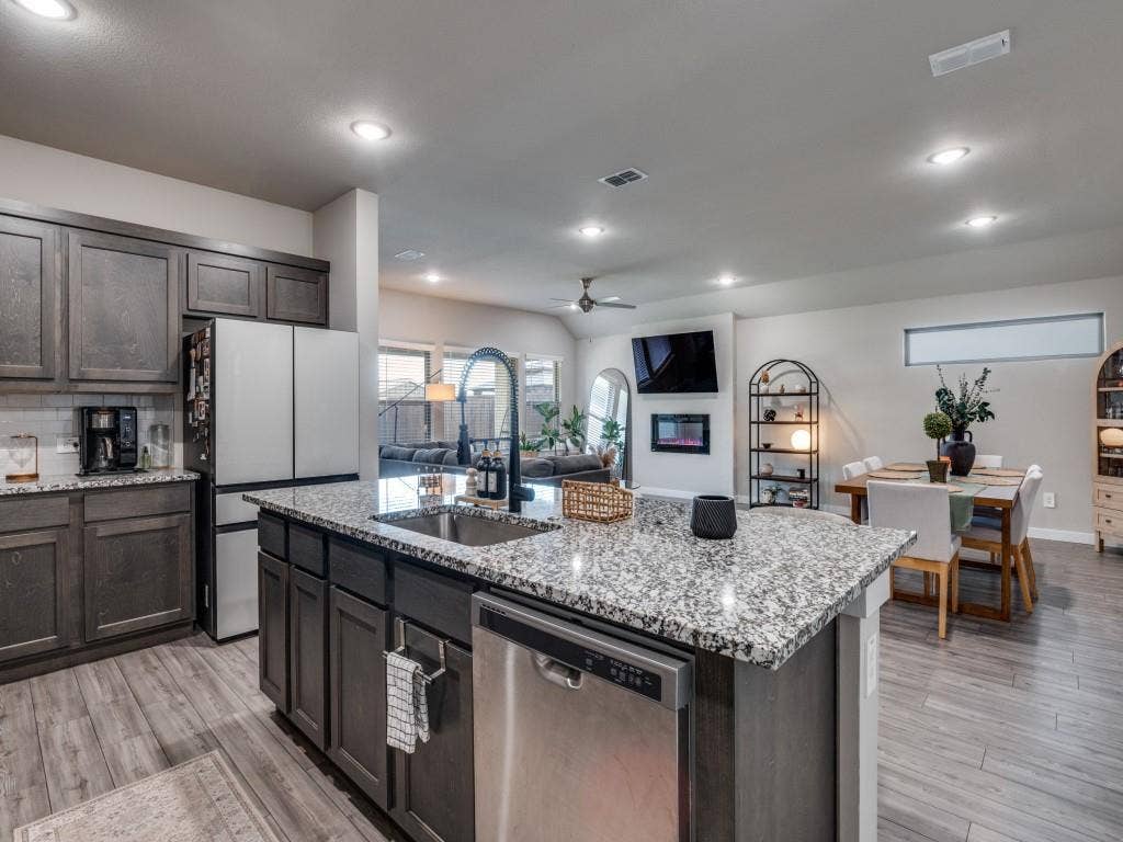 626 Congressional Avenue, Red Oak, TX 75154 Modern kitchen featuring a granite-topped island with an undermount sink and gooseneck faucet, dark wood-finish cabinetry, stainless steel appliances, recessed lighting, and wood-finish flooring