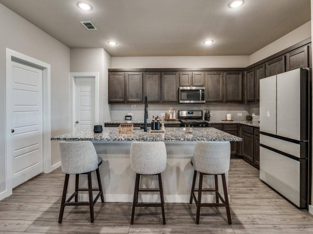 626 Congressional Avenue, Red Oak, TX 75154 Kitchen featuring a spacious island with a light-toned countertop, dark wood cabinetry, stainless steel appliances, recessed lighting, and wood-finish flooring