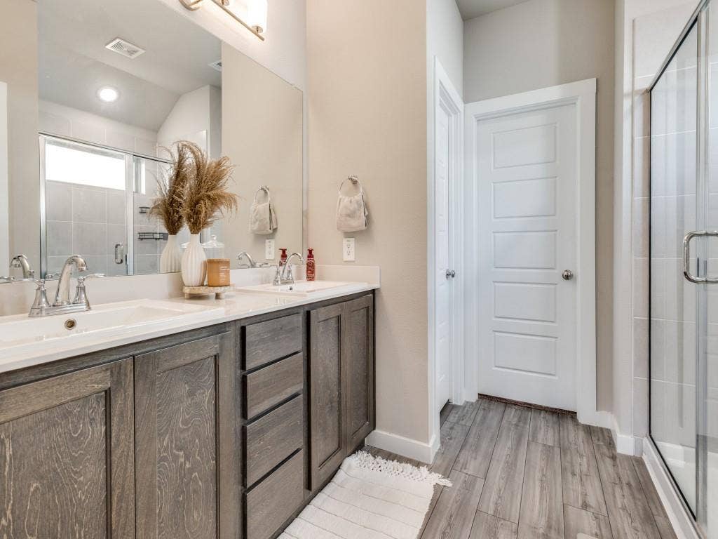 626 Congressional Avenue, Red Oak, TX 75154 Bathroom featuring a dual vanity with undermount sinks, wood-finish cabinetry, and light-toned countertops