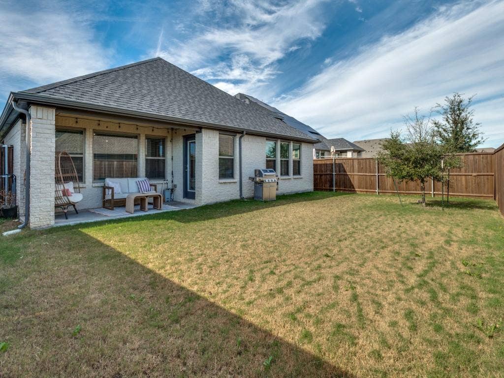 626 Congressional Avenue, Red Oak, TX 75154 Expansive backyard featuring a partially covered patio, brick exterior, dark composition shingle roof, and a wood privacy fence