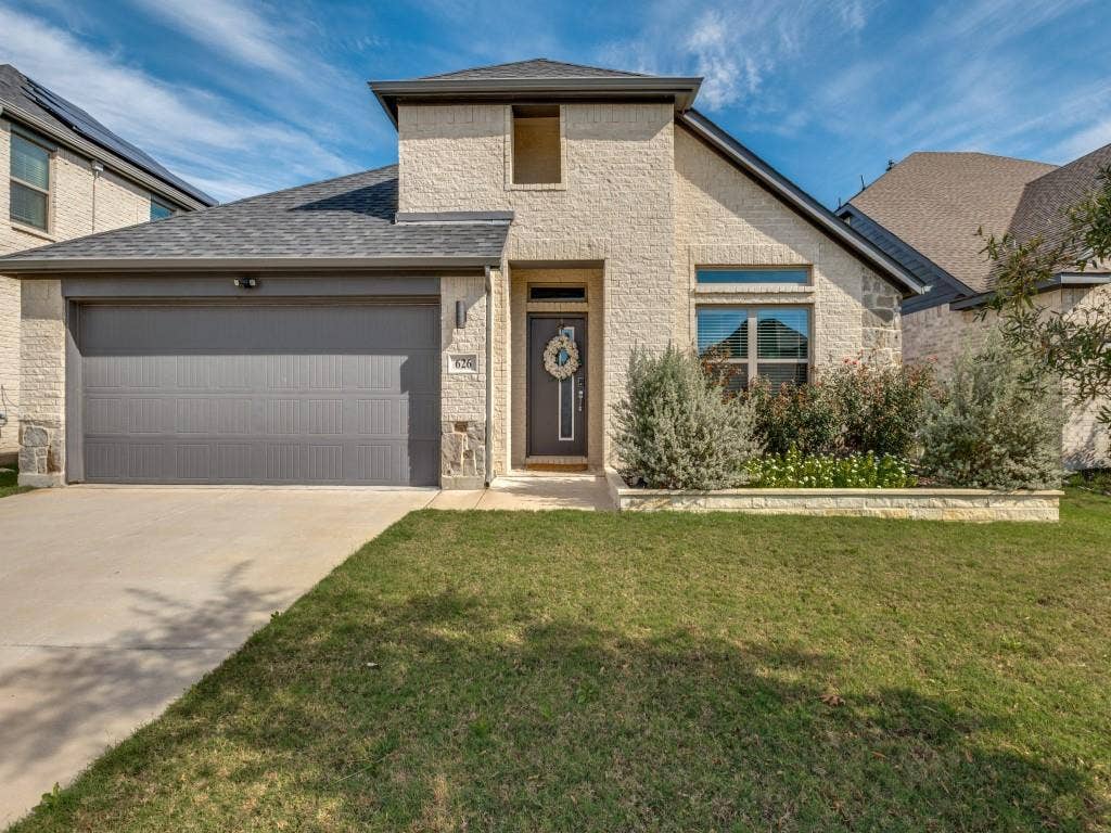 626 Congressional Avenue, Red Oak, TX 75154 Stone and brick veneer facade with a dark gray garage door, a prominent arched window feature, and a paved driveway