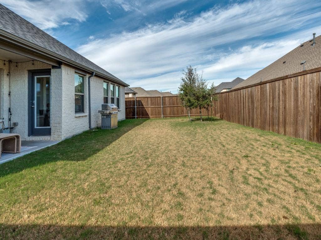 626 Congressional Avenue, Red Oak, TX 75154 Spacious backyard featuring a privacy fence, a young tree, and a concrete patio directly accessible from the dwelling