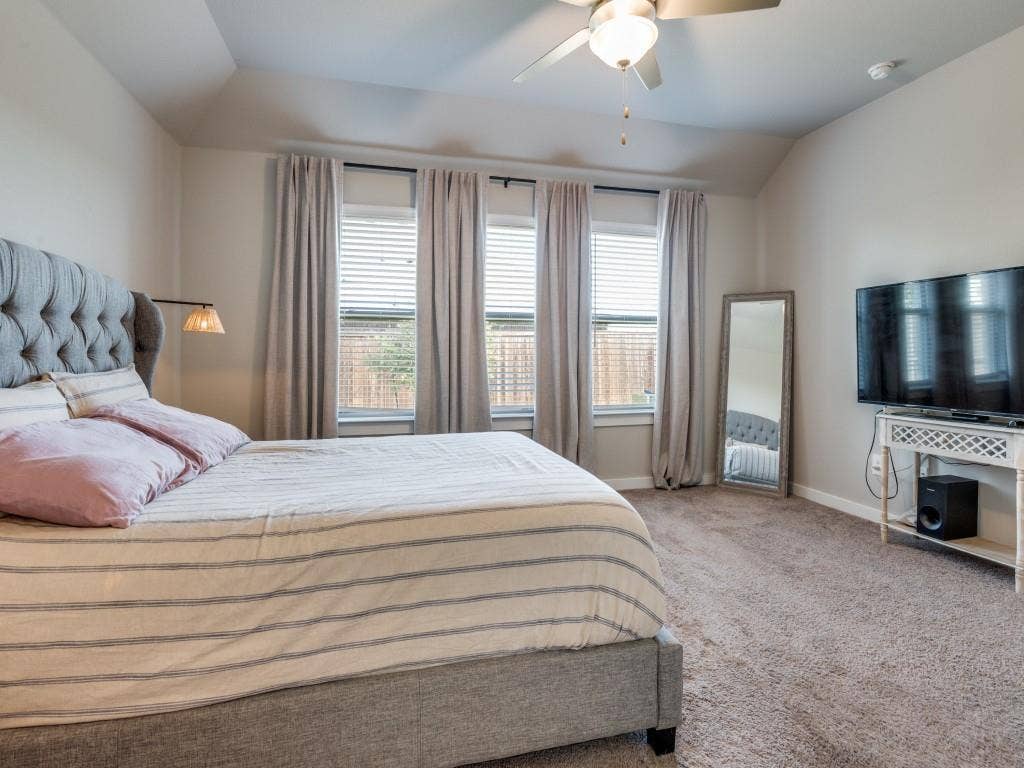 626 Congressional Avenue, Red Oak, TX 75154 Bedroom featuring tray ceiling, ceiling fan with light fixture, three windows with blinds and curtain rods, recessed wall lighting, and plush carpet flooring