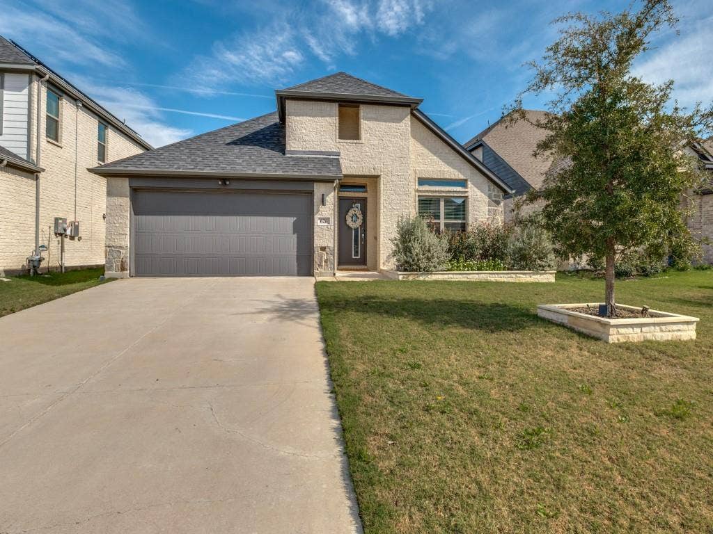 626 Congressional Avenue, Red Oak, TX 75154 Front exterior showcasing a light-colored brick facade with stone accents, a dark gray garage door, and a concrete driveway