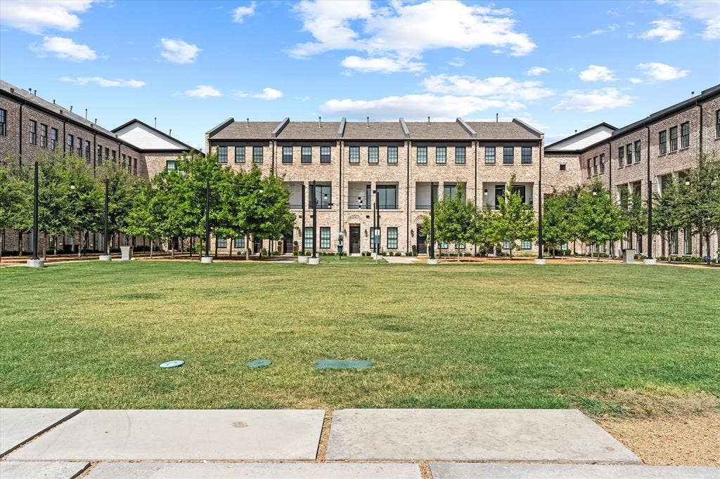 14956 Oak Street, Addison, TX 75001 Community green space with a manicured lawn, framed by modern townhomes featuring brick facades, dark-framed windows, and private balconies