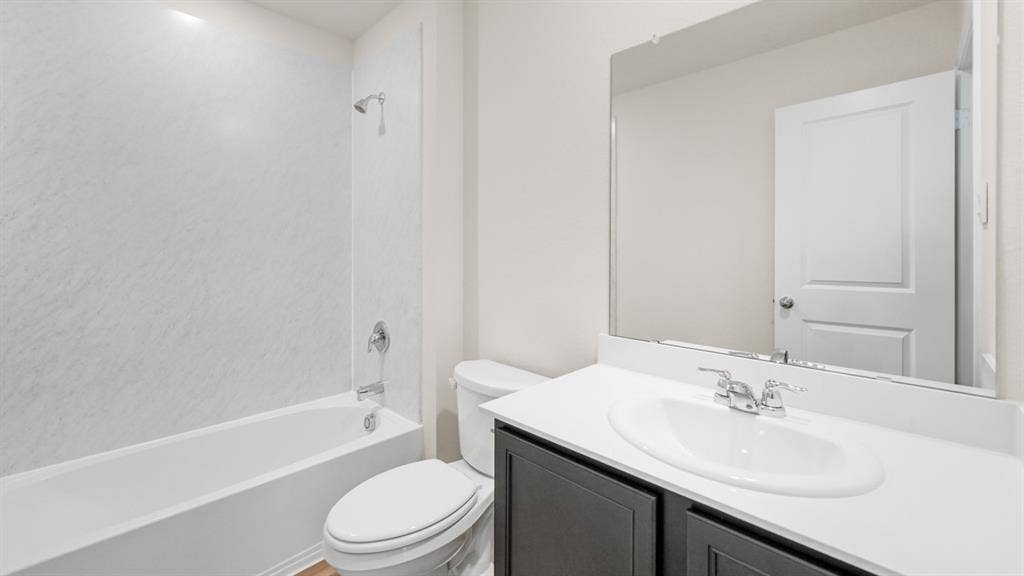 1647 Blaire Drive, Tyler, TX 75702 Bathroom featuring a white tub with shower, chrome fixtures, dark wood-finish vanity, white countertop with integrated sink, and an expansive mirror