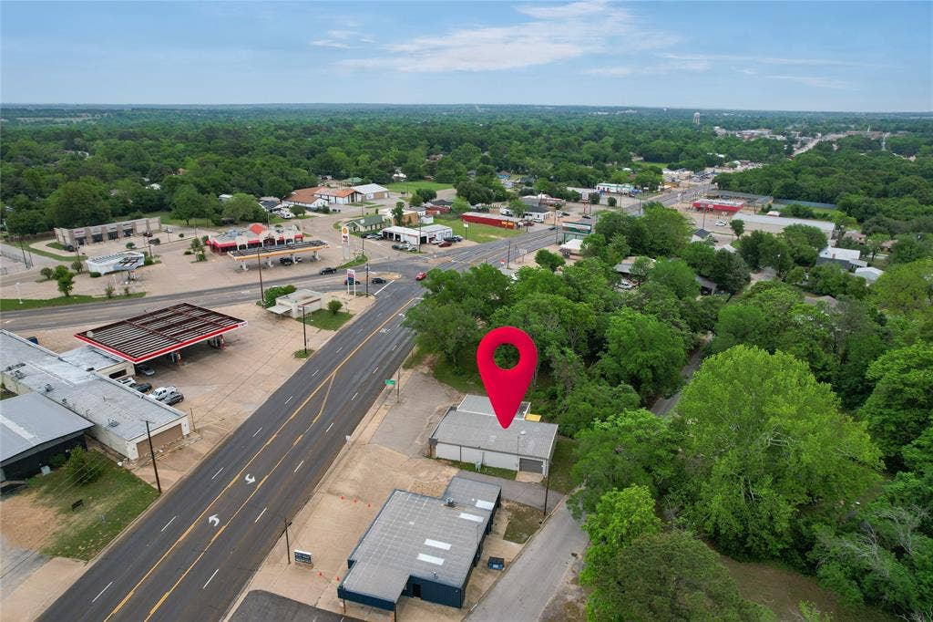 807 W Corsicana Street, Athens, TX 75751 Aerial perspective showcasing a commercial building with a light-colored roof, situated among mature trees