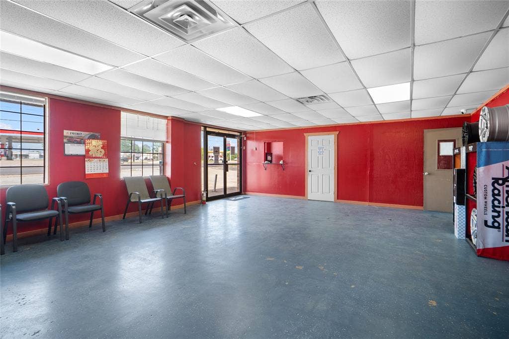 807 W Corsicana Street, Athens, TX 75751 Spacious commercial interior featuring a suspended acoustical tile ceiling with integrated lighting, multiple windows, double glass entry doors, and a durable concrete floor