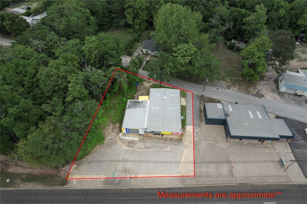 807 W Corsicana Street, Athens, TX 75751 Commercial property featuring a light-colored metal roof and a paved parking area