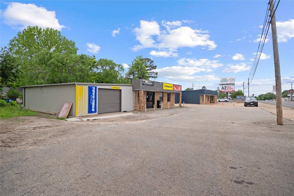807 W Corsicana Street, Athens, TX 75751 Commercial property featuring multiple structures, including a metal-sided building with a roll-up door, a brick-front building with a storefront, and an additional dark-sided structure