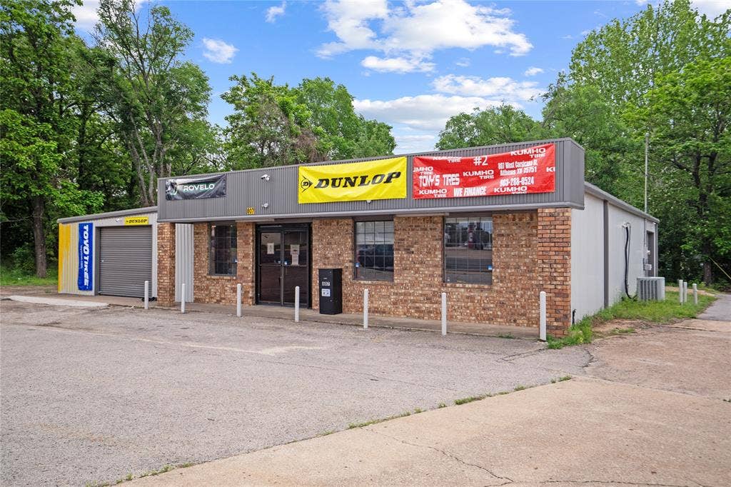 807 W Corsicana Street, Athens, TX 75751 Commercial building featuring a brick facade and a gray roll-up garage door