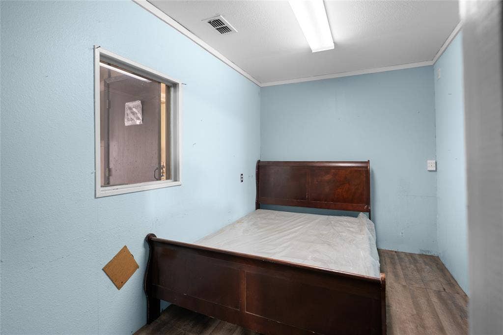 807 W Corsicana Street, Athens, TX 75751 Light blue painted walls with a window, wood-finish flooring, and white ceiling trim